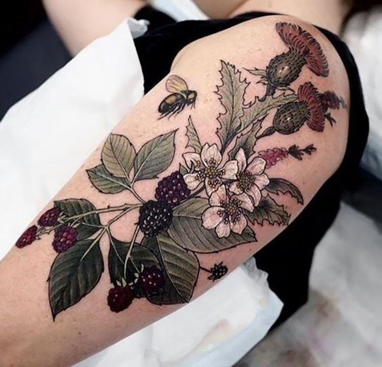 large arm tattoo bee with flowers and berries